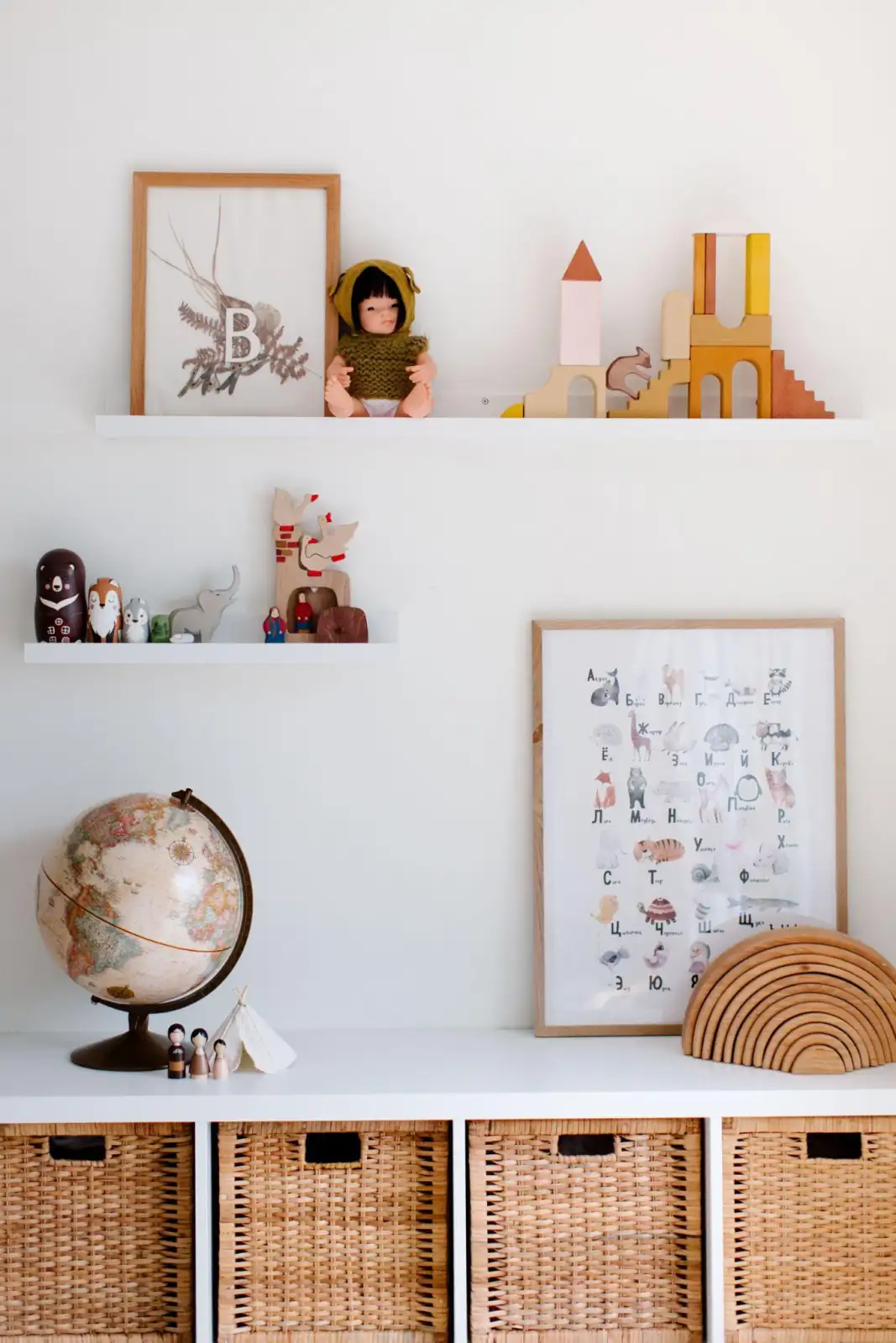 Children's room with open wall shelves, toys, framed artwork, a globe, and woven storage baskets