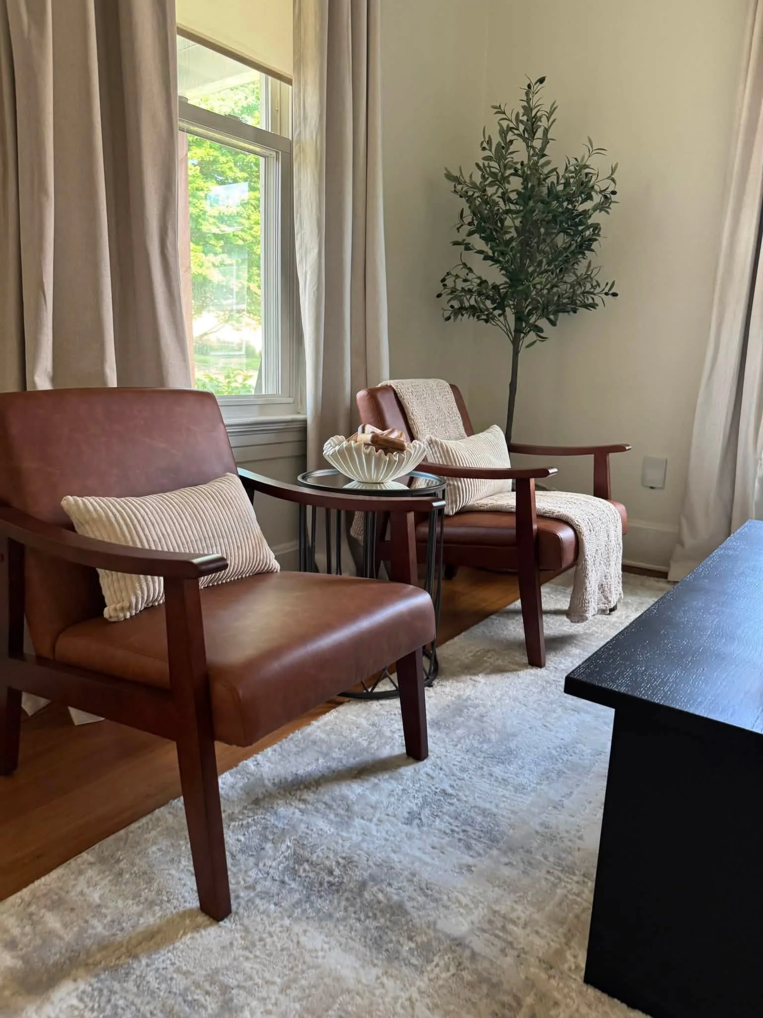 Staged Edwardsville living room with leather chairs, neutral drapery, and daylight