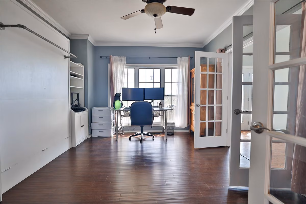 Room with a built-in desk, shelving, and glass doors