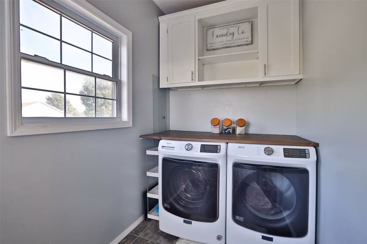 Laundry room with side-by-side washer and dryer beneath built-in storage