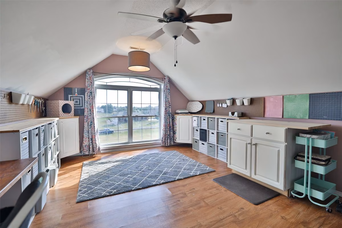 Room with a sloped ceiling, storage cabinetry, and a large arched window